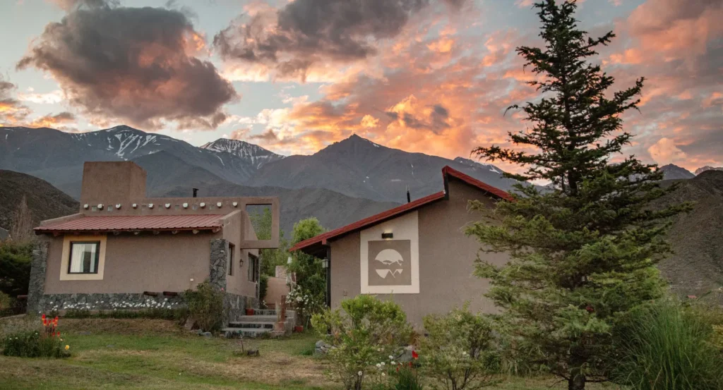 Cabañas en potrerillos con fondo de montañas y atardecer